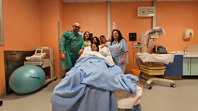 Olivia con mamma e papà e con lo staff sanitario che ha assistito al parto